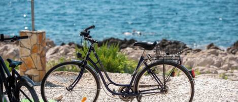 A bicycle parked by a rocky shore with a view of the sea.