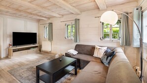 A living room with a flat-screen TV, a sofa, a coffee table, and a lamp. - Holiday Home 'Oberlausitz With 160sqm' with Shared Terrace, Garden, and Wi-Fi (Cunewalde)