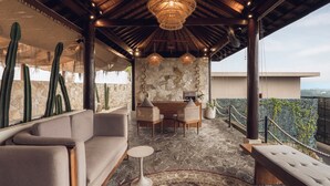 A covered outdoor seating area with a stone floor, cactus plants, and a stone wall with a map. - Seascape Resort & Spa Uluwatu by Ini Vie Hospitality (Pecatu)