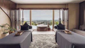 Une salle de spa équipée de deux tables de massage, d’un jacuzzi et offrant une vue sur le paysage urbain.
