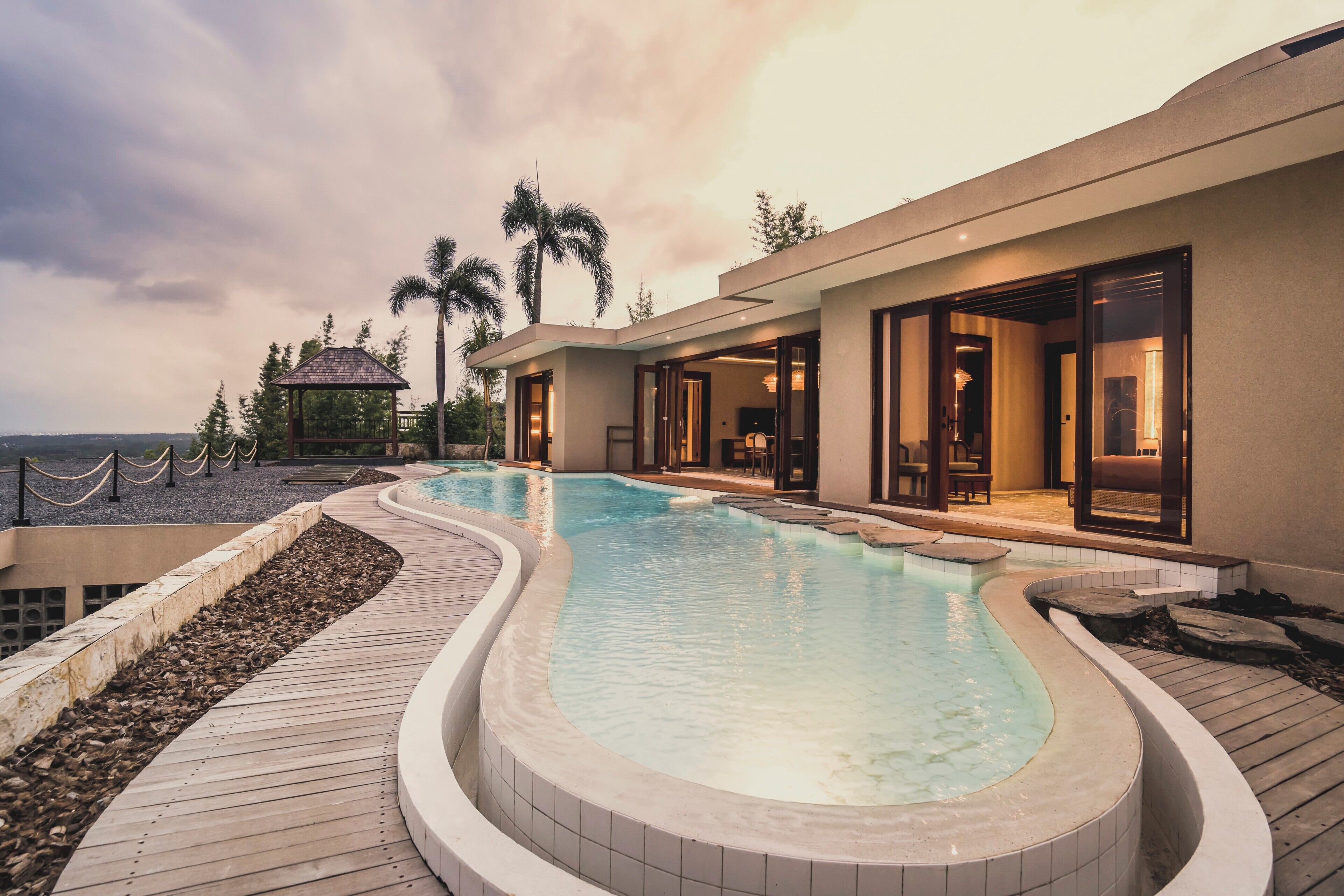 Um resort moderno com uma piscina grande, área de estar externa e vista para o oceano.