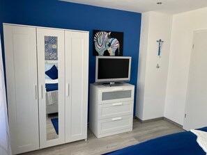 A bedroom with a bed, a wardrobe, a TV on a stand, and a wall with a zebra painting. - Apartment 'Dorfblick' with Private Terrace and Wi-Fi (Olpe)