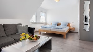 A modern bedroom with a bed, bedside tables, a nightstand, a sofa, and a coffee table with a fruit bowl. - Apartment 'Birnau' with Lake View and Wi-Fi (Hagnau)