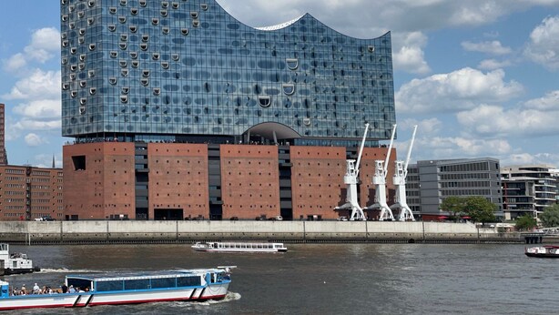 A modern building with a unique curved facade and a river in the foreground.