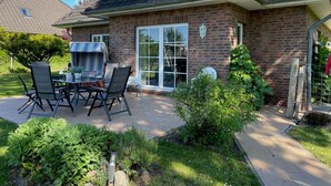 A brick house with a patio, a table with chairs, and a small garden.