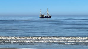 A beach with a boat in the water.