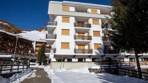 A multi-story hotel with balconies, a snow-covered ground, and a clear sky. - Carlotta whole apartment (Borgata Sestriere)