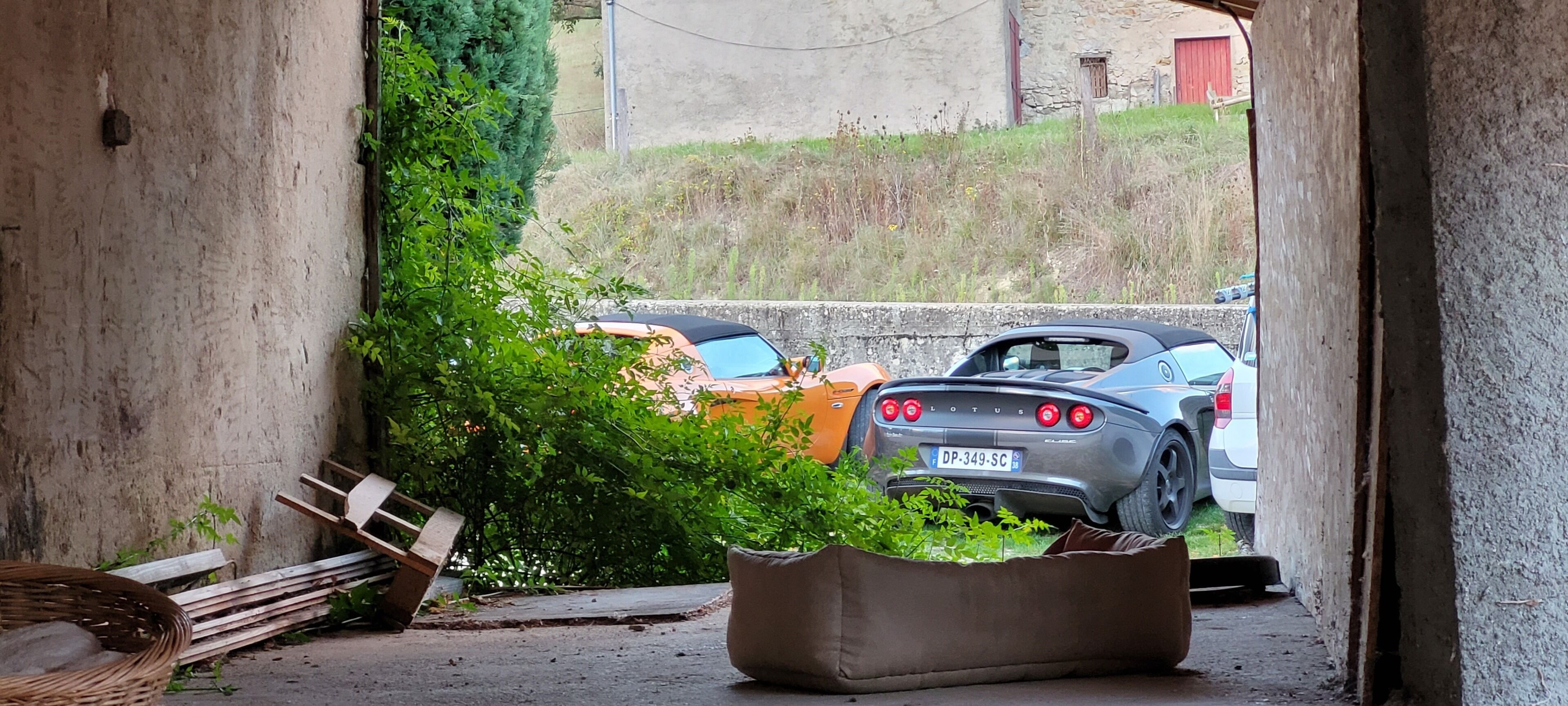 Une voiture était garée dans une allée étroite, bordée d’un mur en béton et d’un banc en bois.