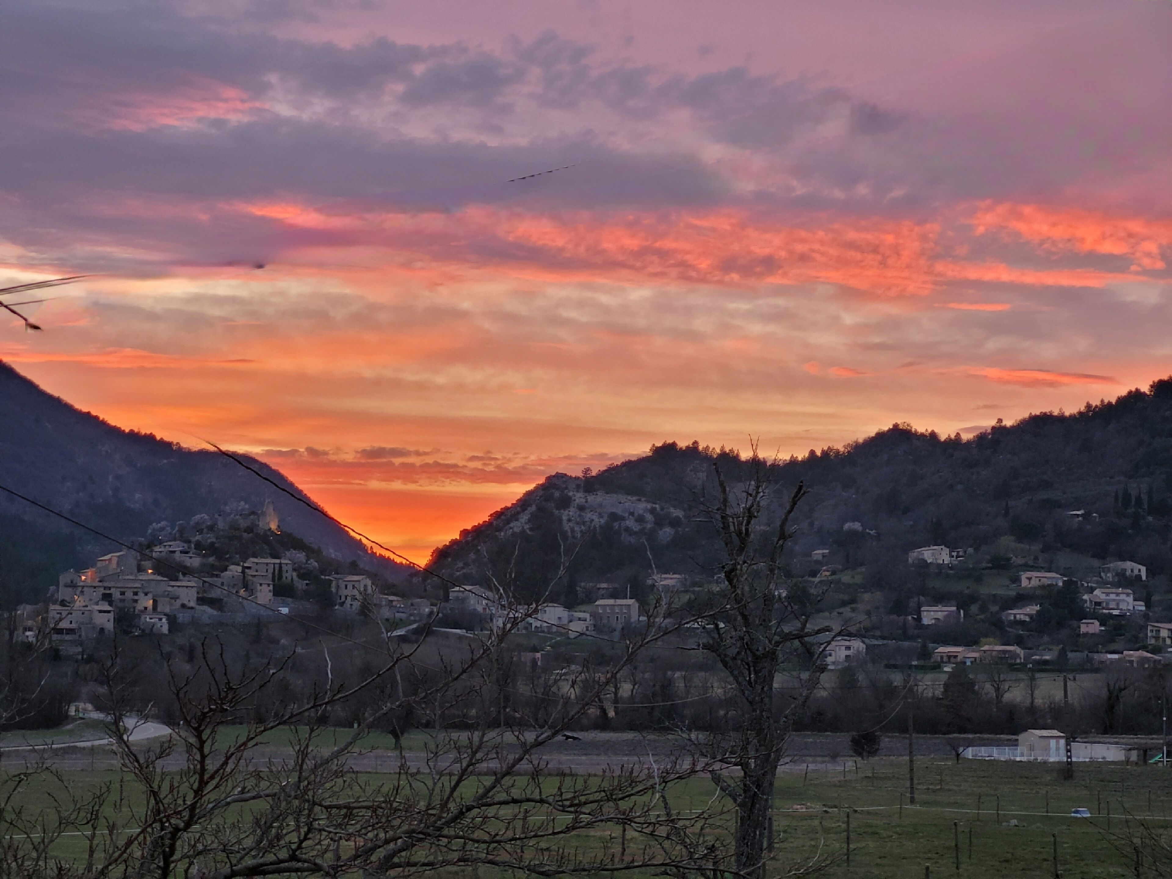 A mountainous landscape with a village at sunset.