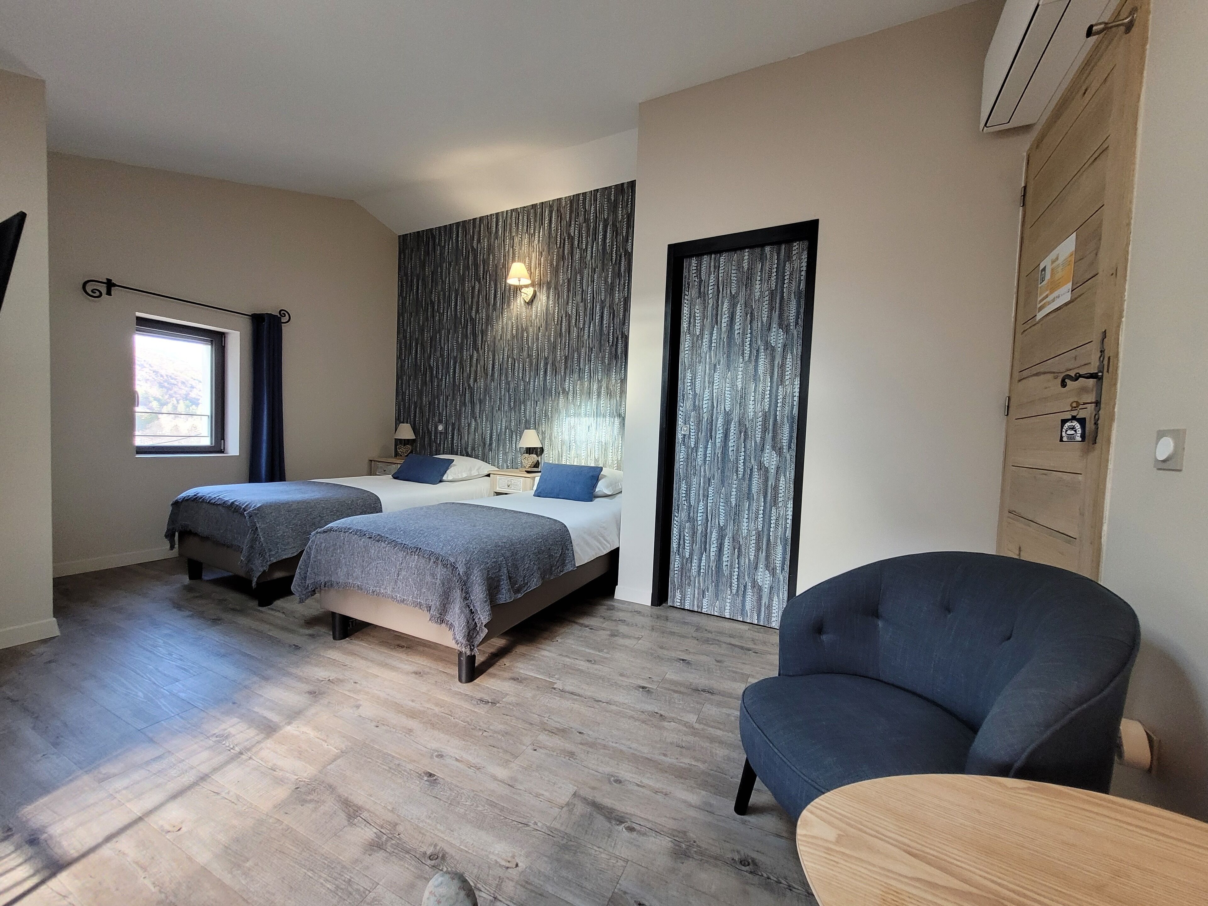 Un dormitorio con dos camas, una silla, una mesa, una ventana y una puerta.