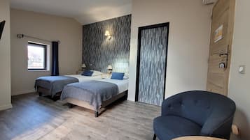 Un dormitorio con dos camas, una silla, una mesa, una ventana y una puerta.