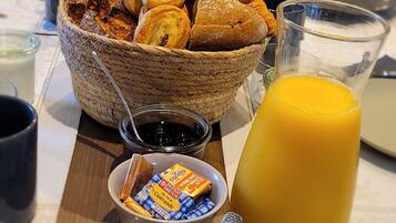 A breakfast buffet with pastries, juice, and condiments.