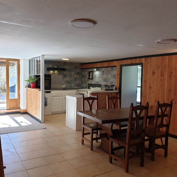A kitchen with a dining area, wooden paneling, and a tiled backsplash. - MAS DE REILHANETTE (Montbrun-les-Bains)