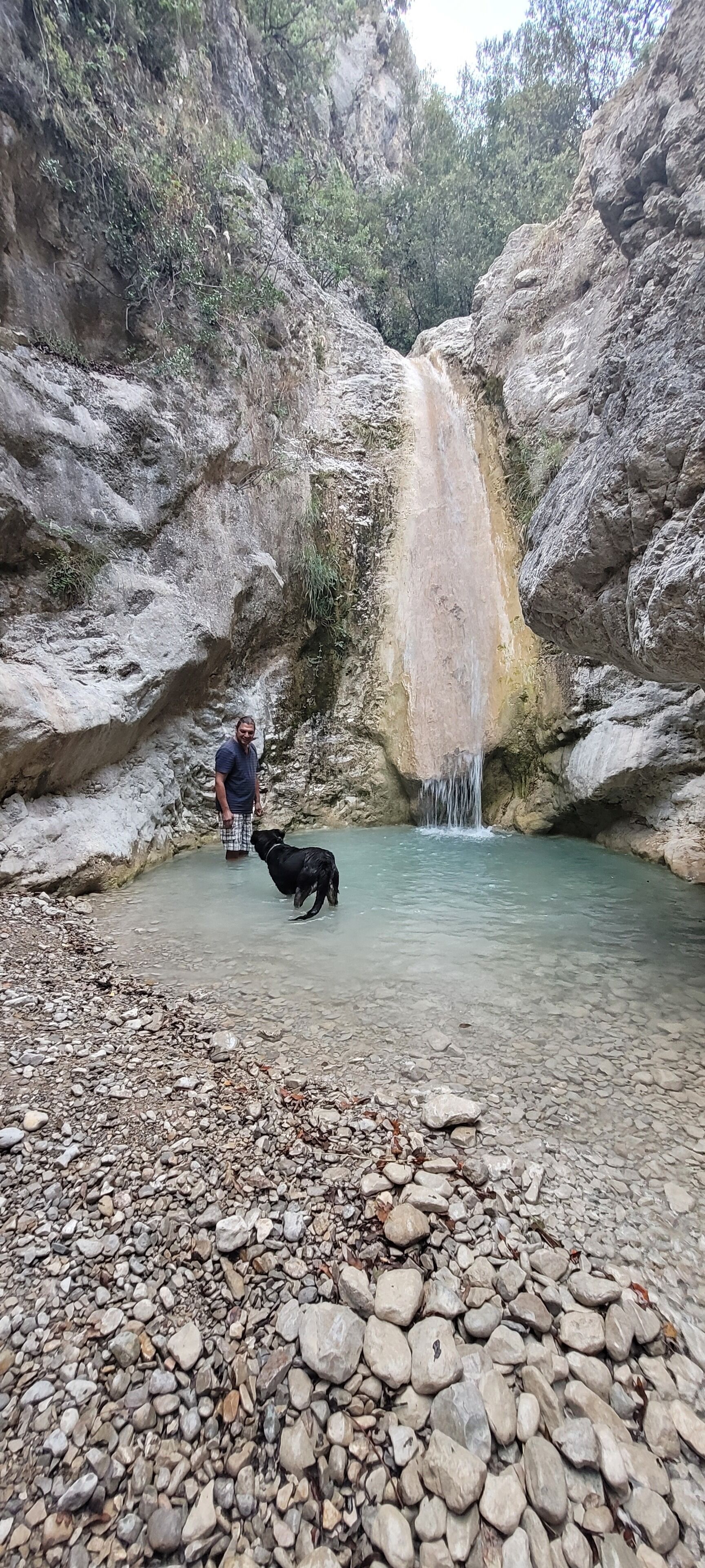 Terreno rocoso con una cascada y una persona de pie junto al agua.