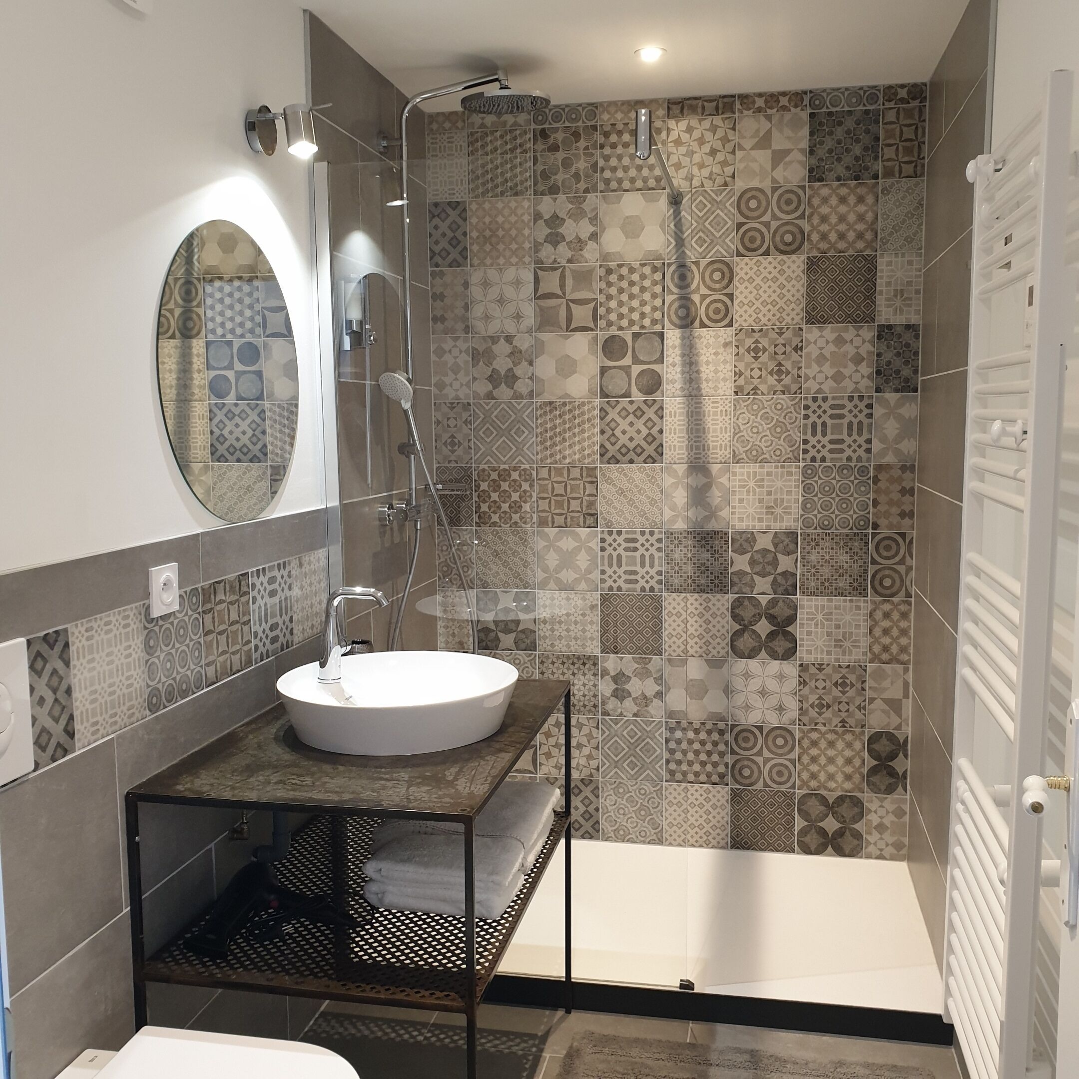 A modern bathroom with a round mirror, a sink, and a shower.