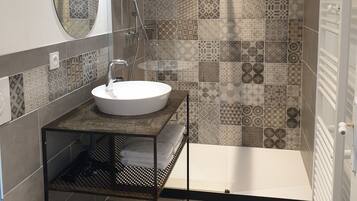 A modern bathroom with a round mirror, a sink, and a shower.