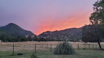 A rural landscape with a village nestled in the valley, surrounded by hills and a clear sky.