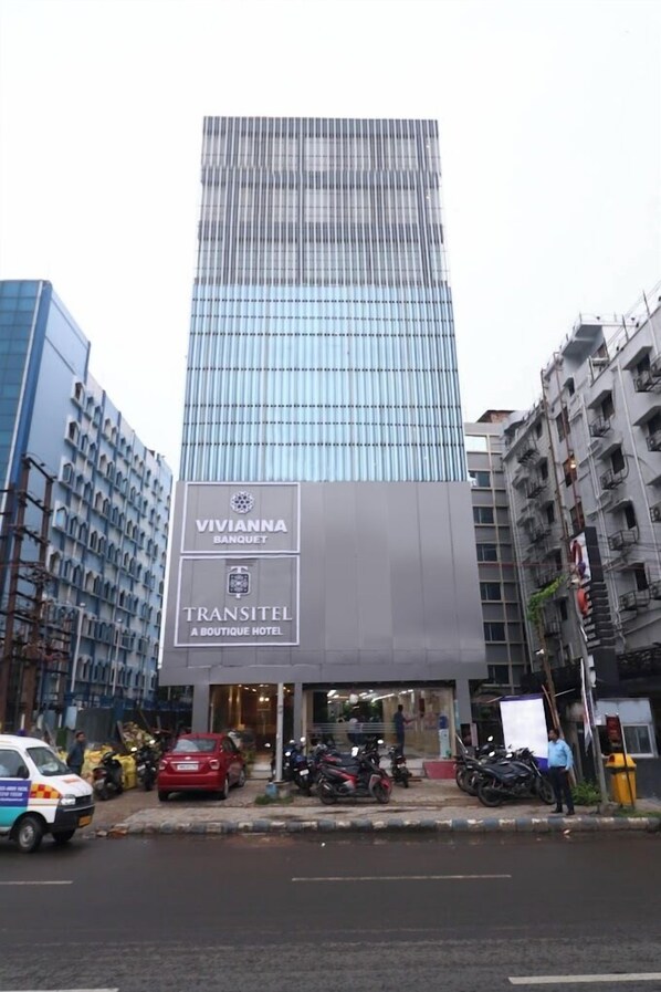Un bâtiment moderne avec une grande enseigne indiquant « Vivianna Banquet » et « Transitel Boutique Hotel ».