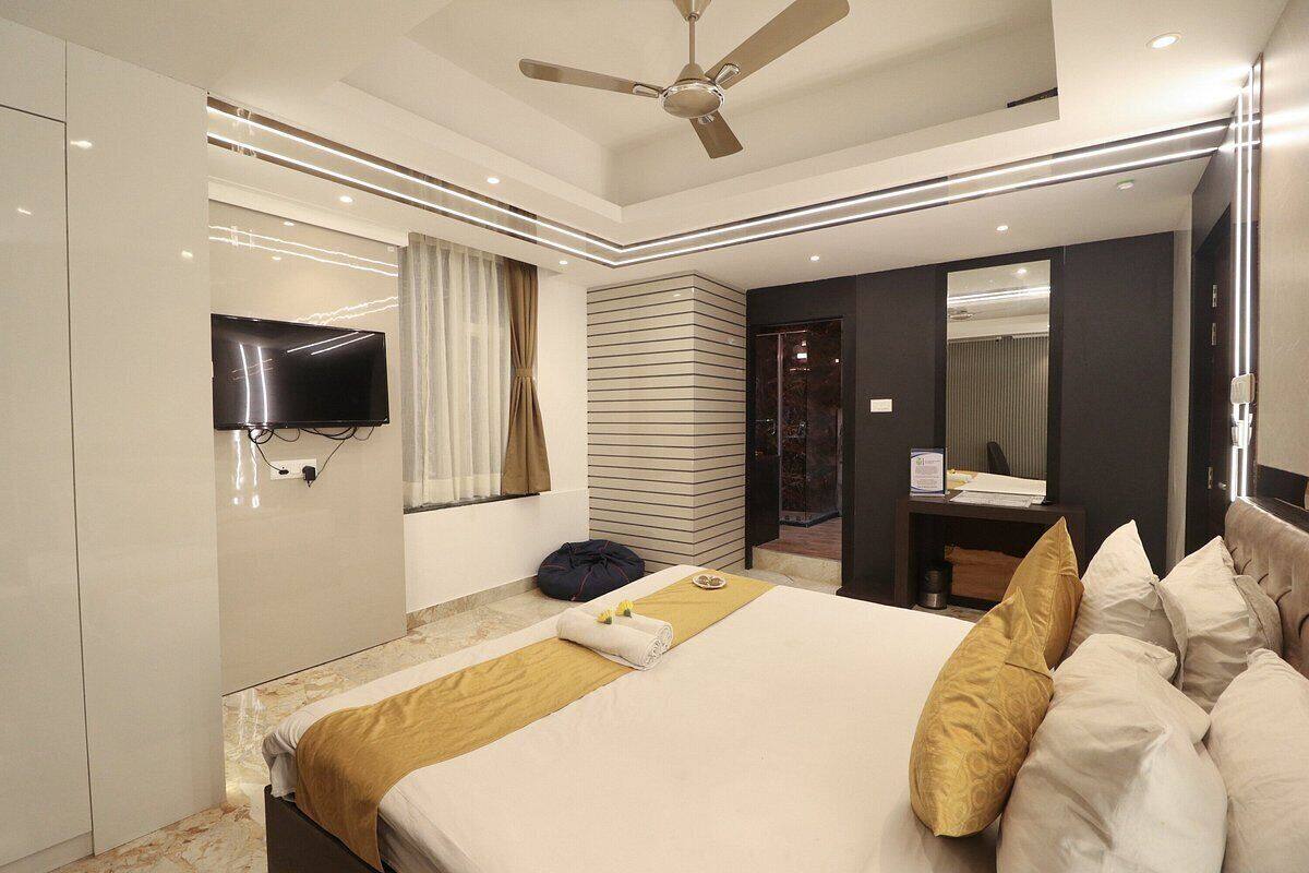 A modern hotel room with a bed, a television, a ceiling fan, and a bathroom visible through an open door.