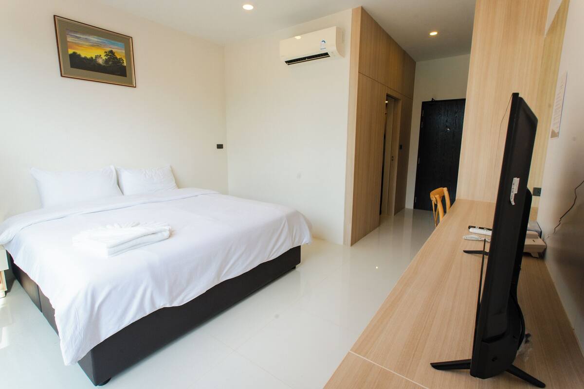 Ein modernes Hotelzimmer mit einem großen Bett, einem Flachbildfernseher und einem Holztisch.