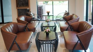 Een moderne zithoek met leren fauteuils en een centrale tafel met een bloemenvaas.