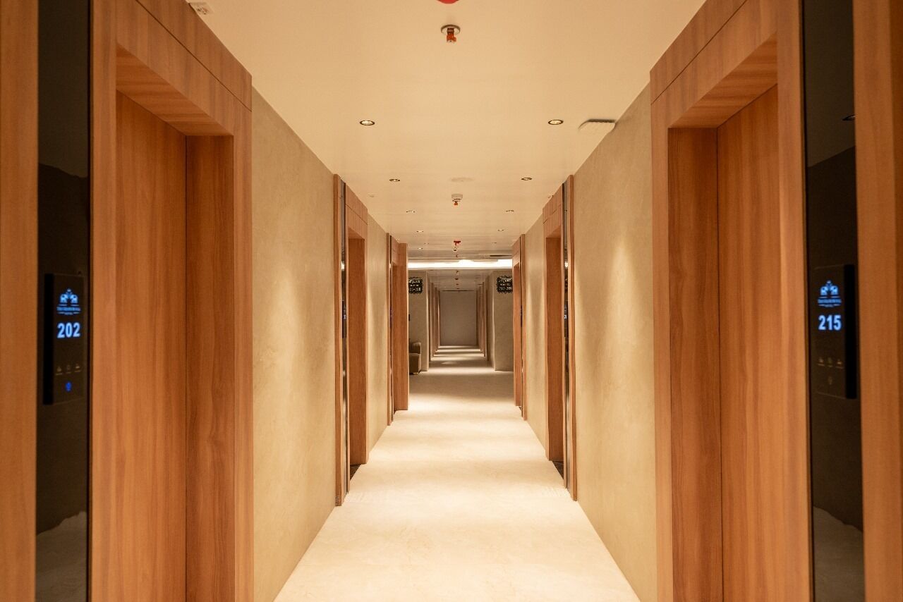 A modern hotel corridor with wooden paneling and a carpeted floor.