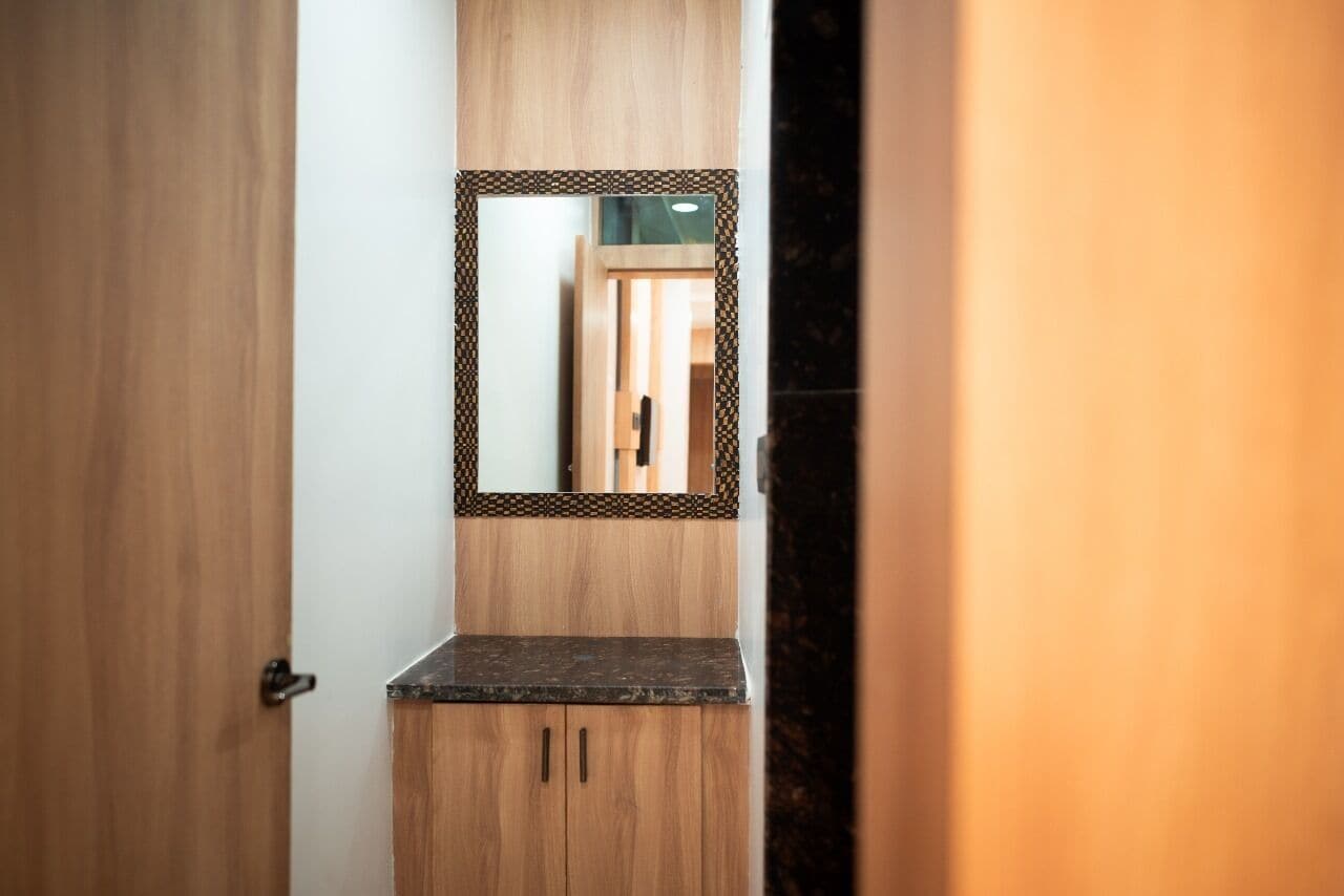 Una puerta de madera con un espejo sobre una encimera oscura y armarios de madera.