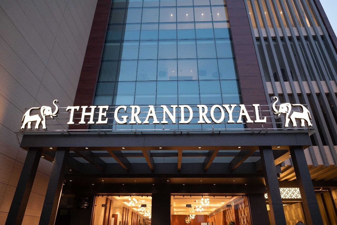 Fachada moderna del hotel The Grand Royal, con señalización iluminada.