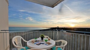 A balcony with a round table, chairs, and a view of the sea at sunset. - Sunset terrace escape by Beahost Rentals (Lignano Sabbiadoro)