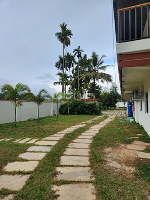 A pathway leading to a building with a white exterior and a balcony. - Falls Regency (Vilavancode)