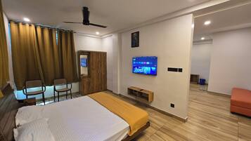 Una habitación de hotel moderna con una cama, un televisor montado en la pared, un ventilador de techo y piso de madera.