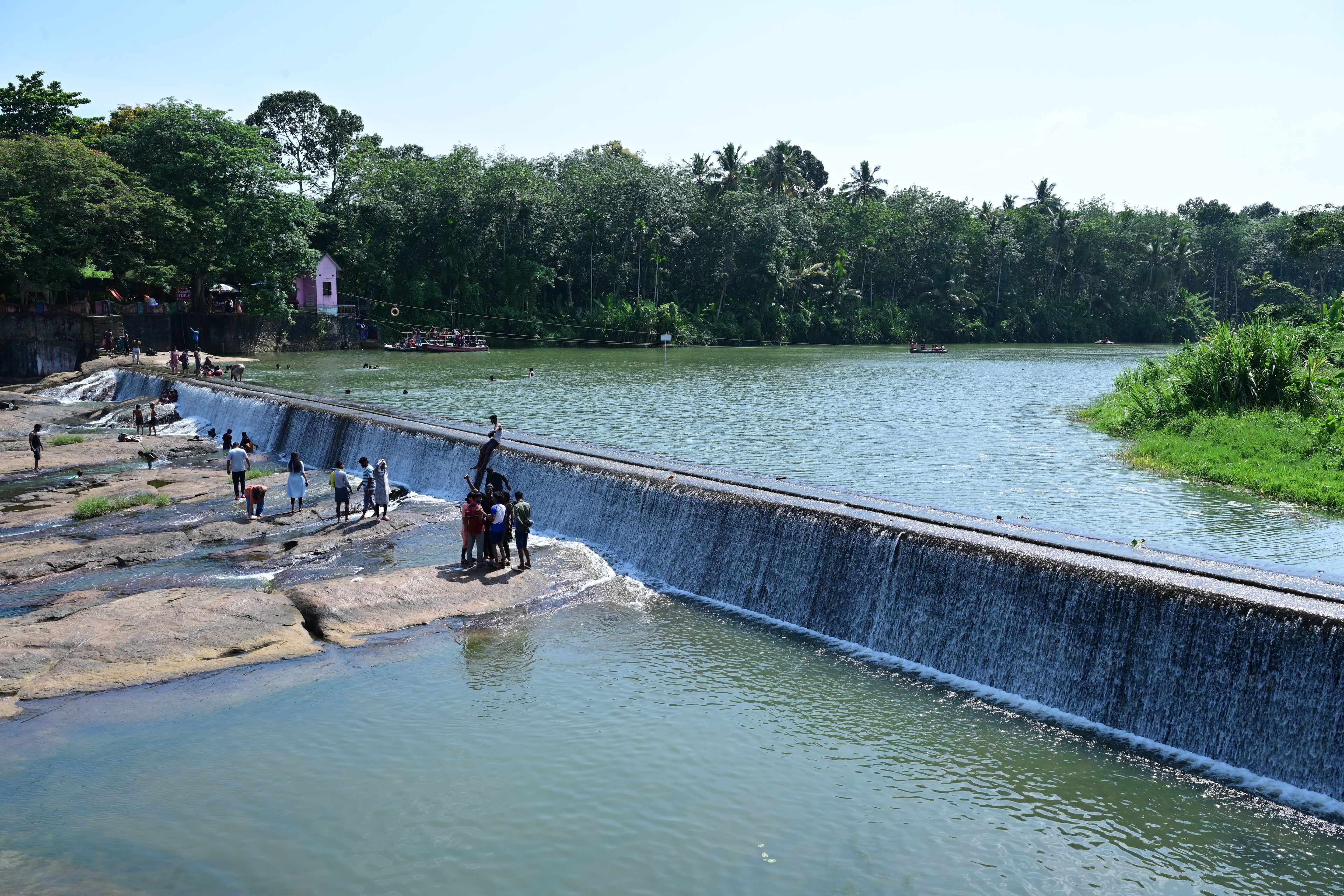 A river with a dam and people standing on the rocks.