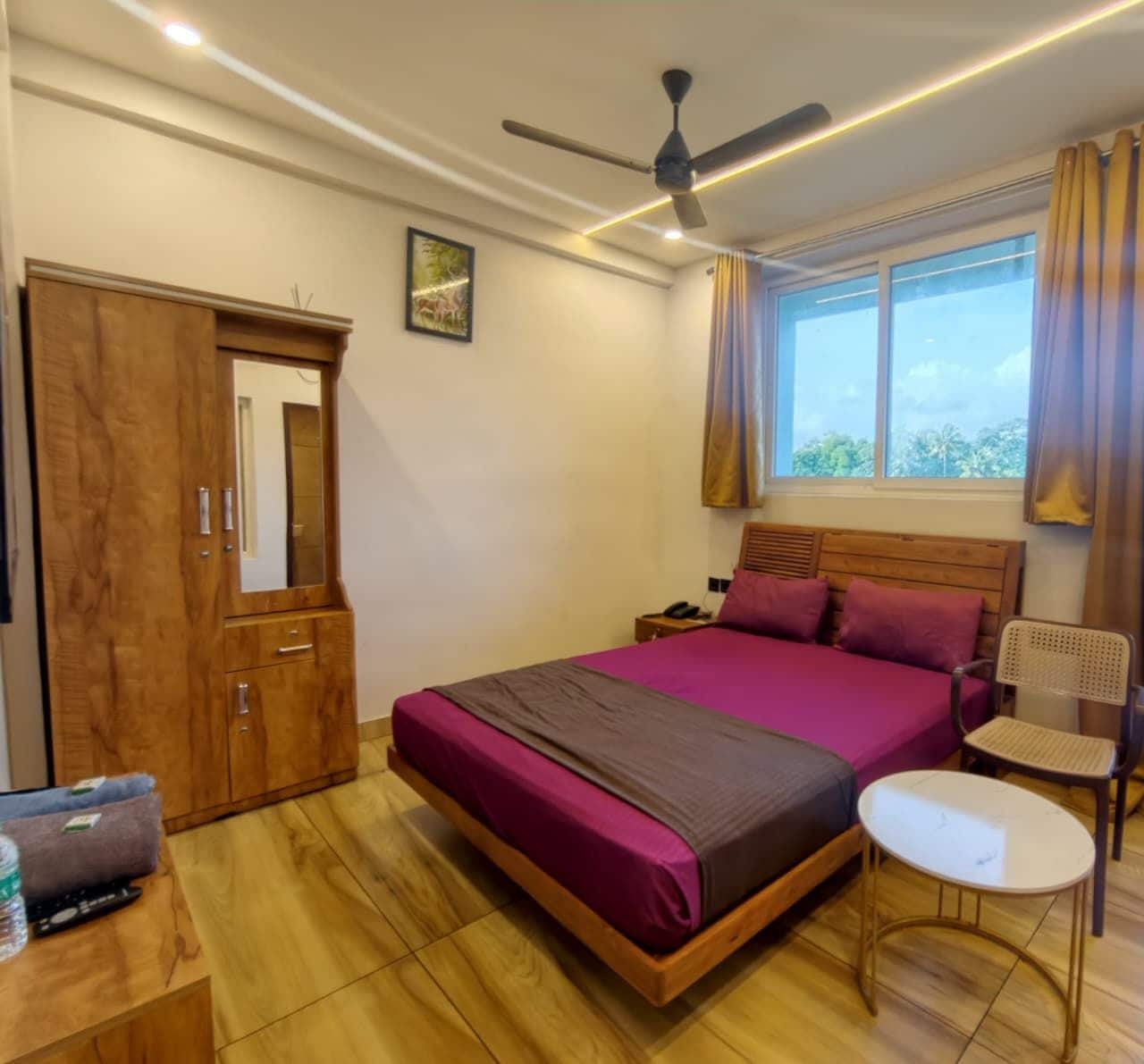 Ein Schlafzimmer mit Bett, Nachttisch, Stuhl, Kleiderschrank und Deckenventilator.
