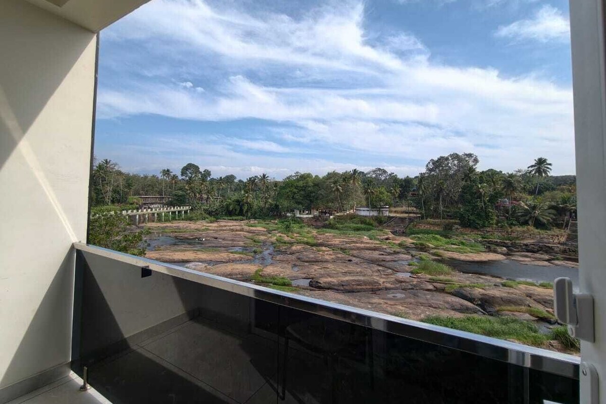 A balcony with a view of a rocky landscape, trees, and a bridge in the distance.