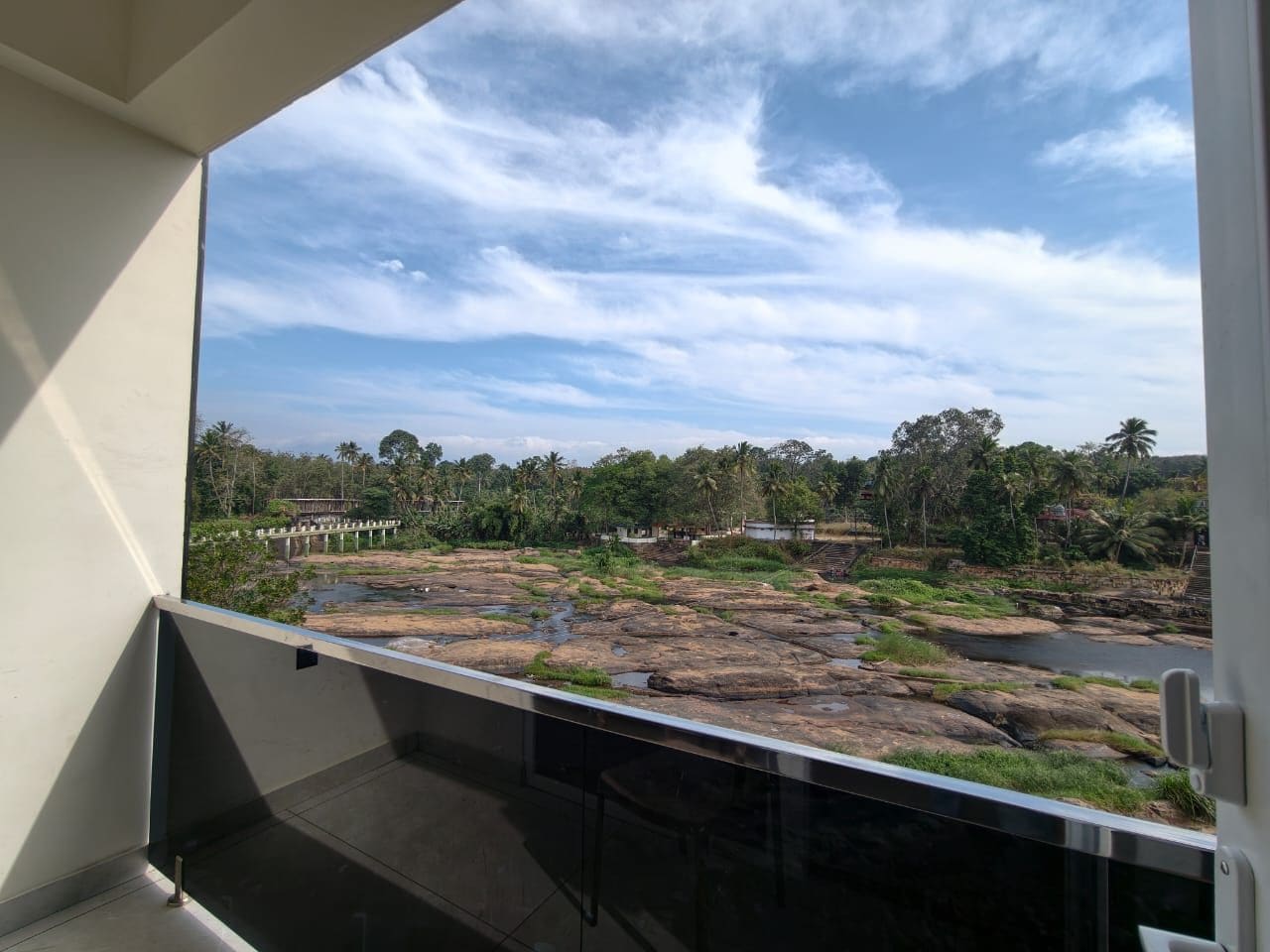 A balcony with a view of a rocky landscape, trees, and a bridge in the distance.