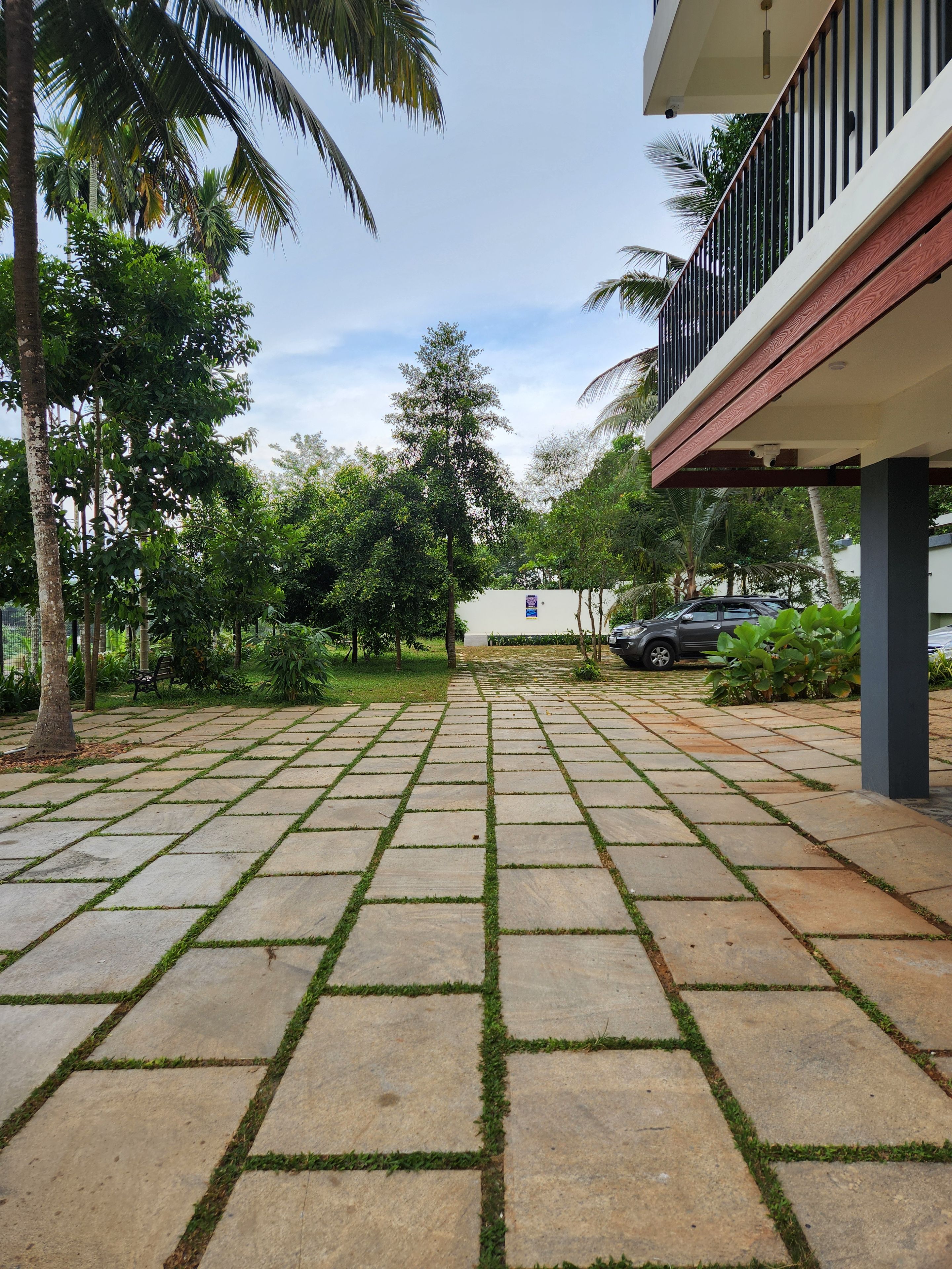 Un patio empedrado con suelo de baldosas, rodeado de follaje y palmeras.