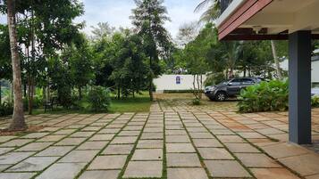 Un patio empedrado con suelo de baldosas, rodeado de follaje y palmeras.