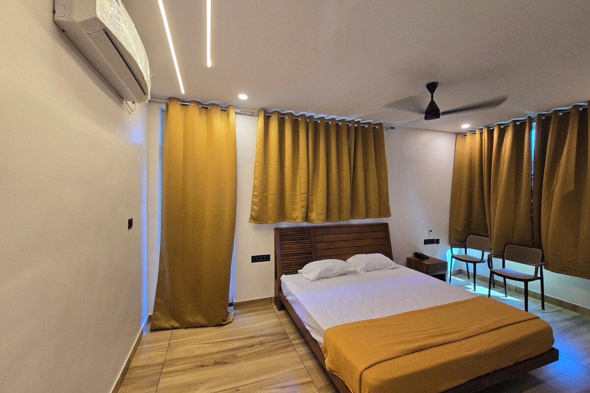 A bedroom with a bed, a nightstand, a chair, and a ceiling fan.