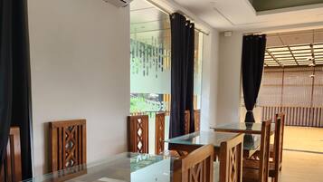 Uma sala de jantar com mesa de vidro, cadeiras de madeira e ar condicionado na parede.