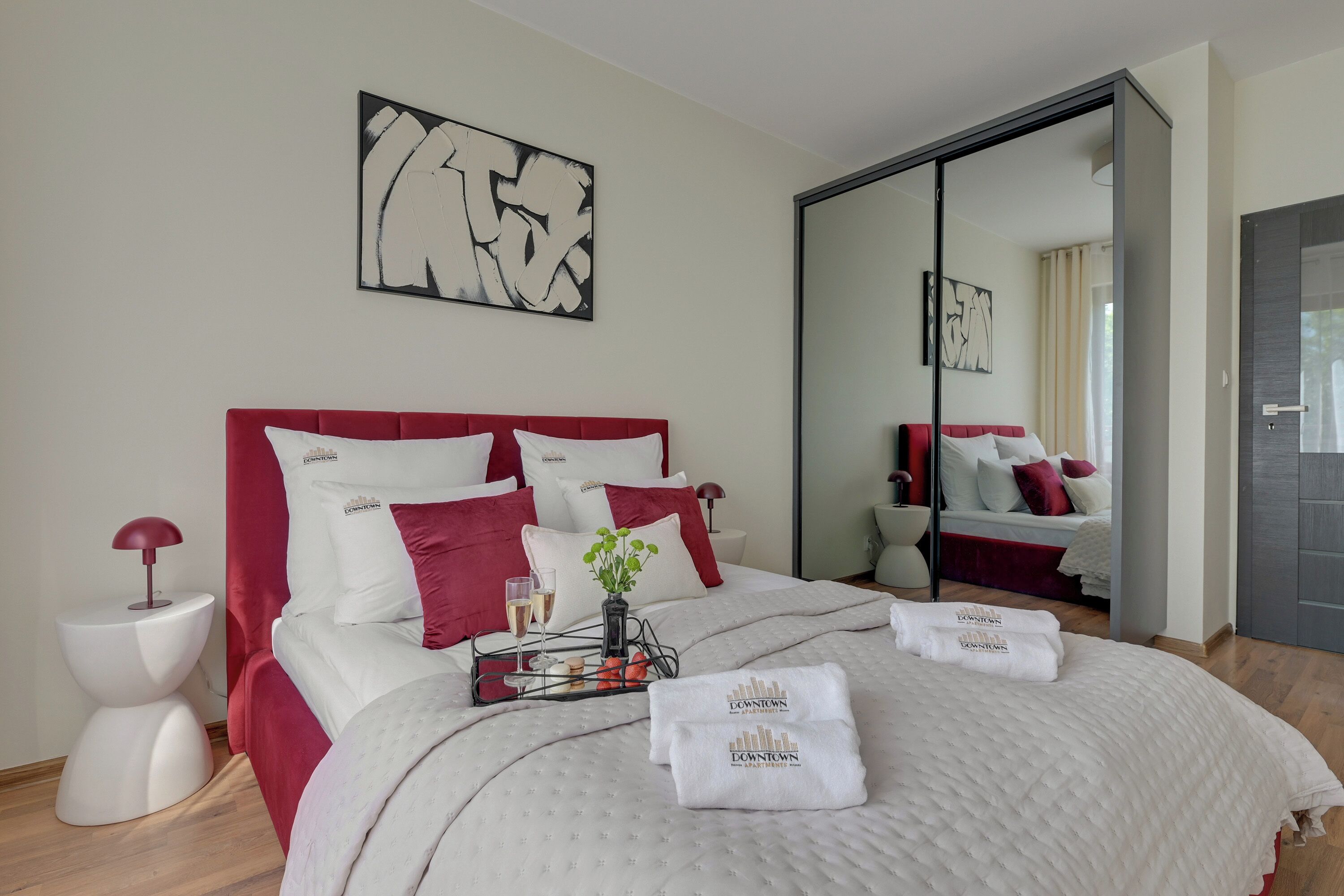 Un dormitorio de hotel con una cama grande, una mesita de noche, un espejo y cuadros en la pared.
