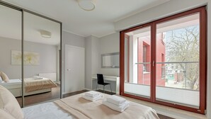 Une chambre moderne avec un grand lit, un bureau et une vue sur l’extérieur.