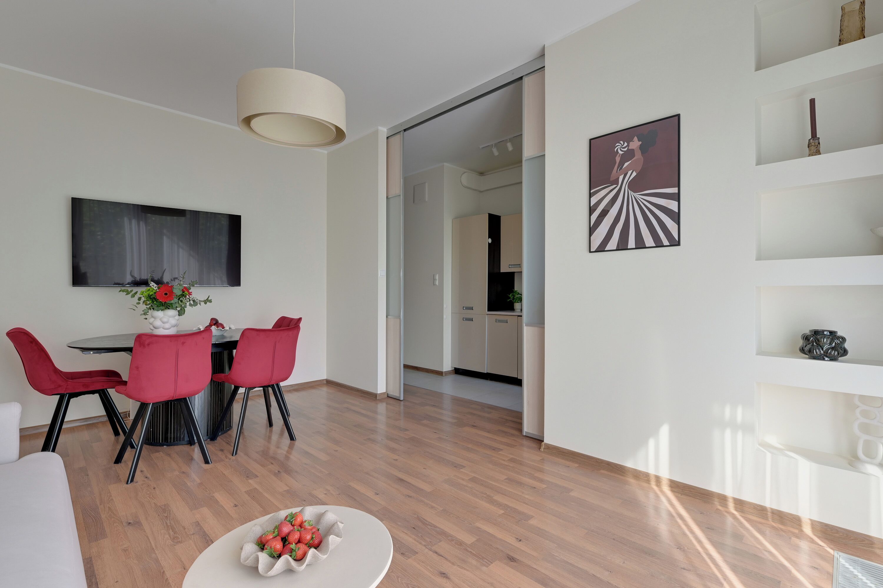 A modern living space with a dining area, a kitchen, and a hallway.