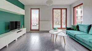 Un salon moderne avec un canapé turquoise, un meuble de rangement pour appareils multimédias blanc et une table basse blanche.