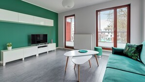 Un salon moderne avec un canapé vert, un meuble TV blanc et une table à manger.