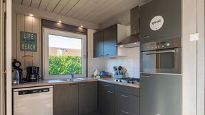 Una cocina moderna con armarios grises, lavavajillas, estufa y un ventanal grande.