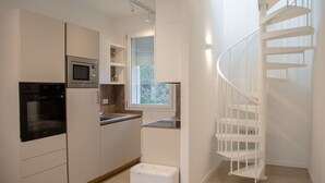 A modern kitchen with built-in appliances, a window, and a white spiral staircase. - Nice apartment for 4 people with A/C, WIFI, TV and terrace (Ca' Savio)