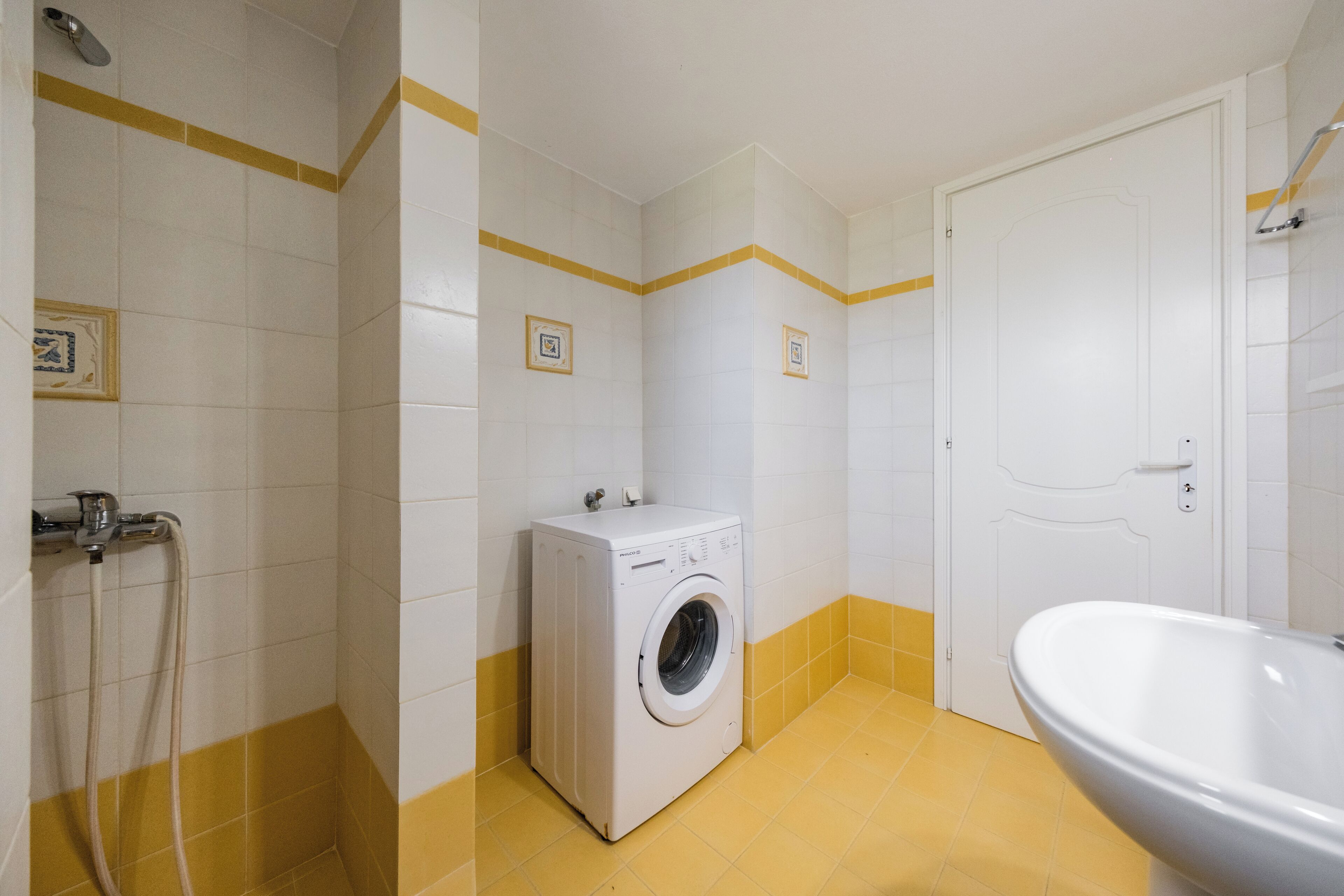 Un baño pequeño con lavadora, ducha y lavamanos.