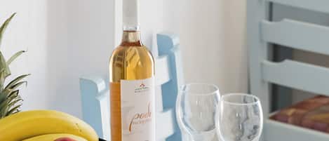 A table with a fruit basket, a bottle of wine, and two wine glasses.