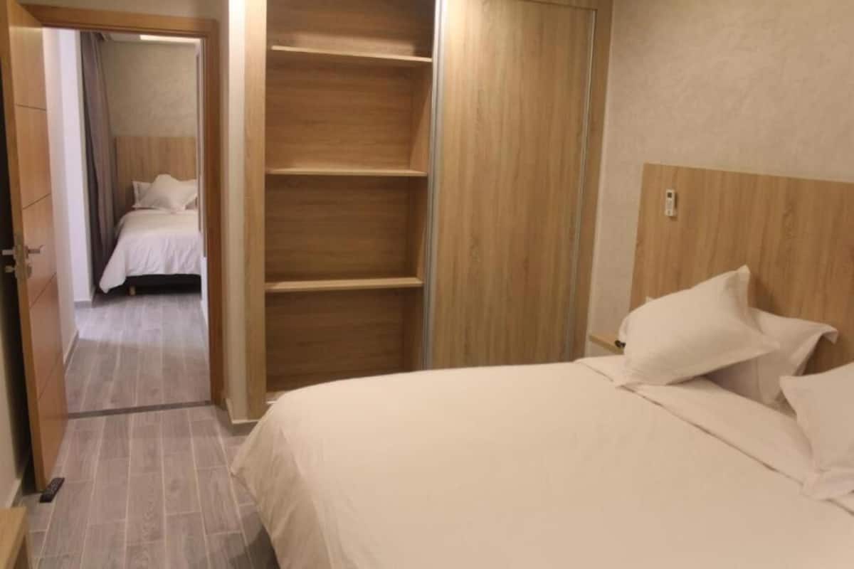 Un dormitorio con cama, un armario de madera y una puerta que da a otra habitación.