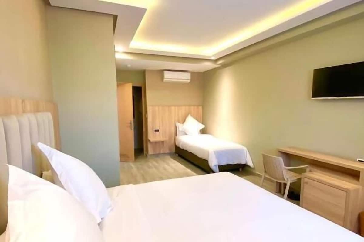 Habitación de hotel con dos camas, un escritorio y un televisor.